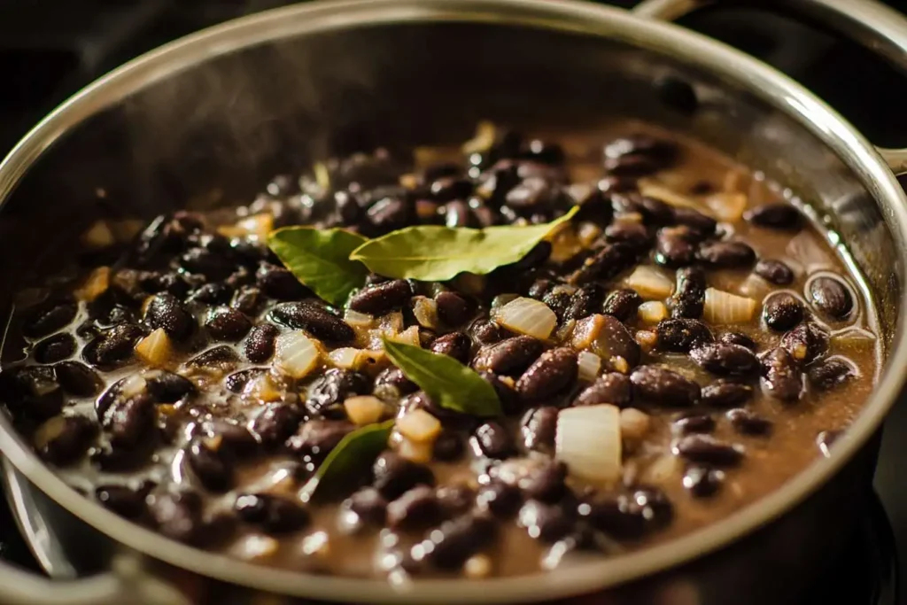 Black beans simmering in a pot with garlic and bay leaves for extra flavor.